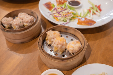 Kanom Jeeb or Steamed Pork and Shrimp Dumplings in a bamboo steamer. Shumai is a chinese cuisine dish with minced pork meat, shrimps, and vegetables. Chinese food