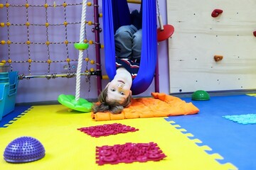 child boy guy in a hammock at the children's center for children with special needs and correction is undergoing a course of rehabilitation treatment autism flight coup learning independence