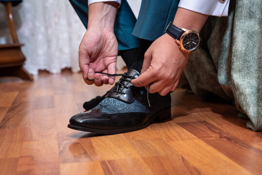 The groom tying his shoes before his wedding