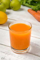 Carrot apple and celery juice on a white old table with ingredients. Selected focus.