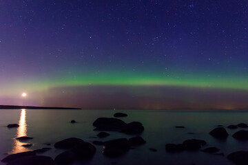 Arcuate aurora green above the lake with moon
