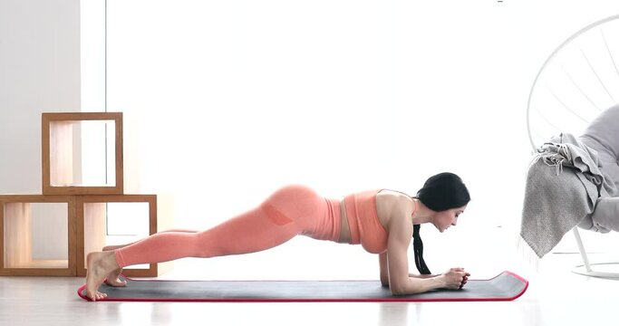 Fitness woman doing abs crunches exercise lying flat on floor training at home. Abdominal muscles workout, body flexing routine concept.