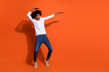 Fototapeta na wymiar Photo of cute attractive cheerful guy wear white shirt dancing empty space isolated orange color background