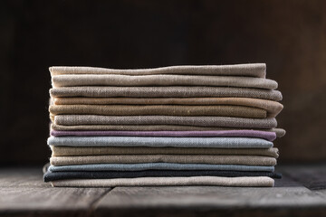 A pile of four folded dull-colored natural linen fabric