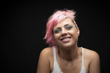Naklejka premium Caucasian blonde woman with pink hair and green eyes smiling at camera