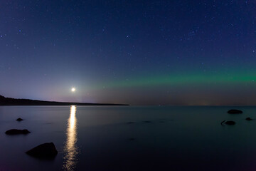 Fototapeta na wymiar Arcuate aurora green above the lake with moon