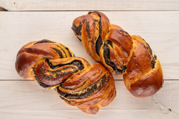 Two flavorful homemade poppy seed rolls on a wooden table, macro, top view.

