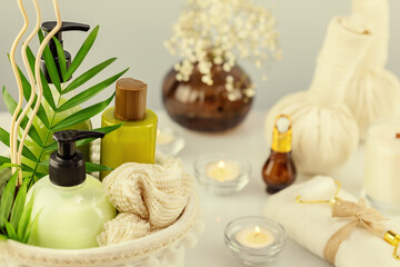Obraz na płótnie Canvas Bath relax still life with spa accessories, cosmetics, candles and towel on a white table with palm leaves. Wellness and skin care treatment. Concept of me time and no depression. Soft focus