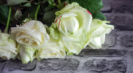 A beautiful bouquet of white roses on a background of stone paving stones. A bouquet of flowers illuminated by soft light.