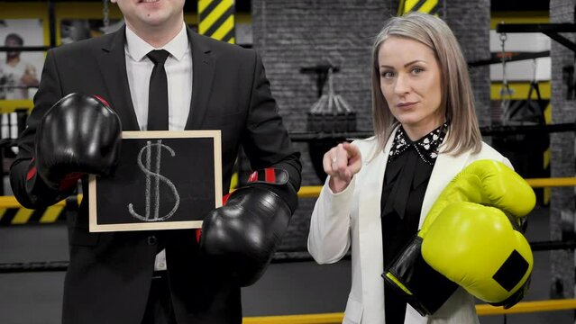 Man and a woman businessmen in suits and boxing gloves hold a sign with a dollar sign in their hands