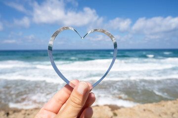 Sea view through shape of heart in the female hand of tropical beach. Valentines day. Holiday, vacation concept. Creative, background, copy space, travel, summer.