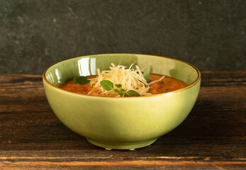 Vegetable soup in a green bowl on a dark wooden background
