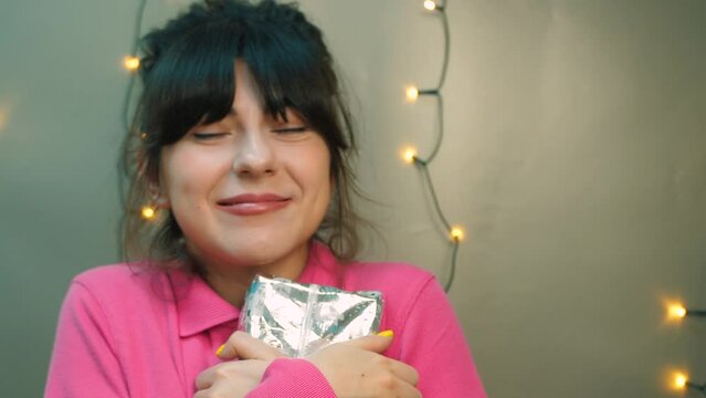 A happy young woman holding a gift box, feeling excited for finally receiving it