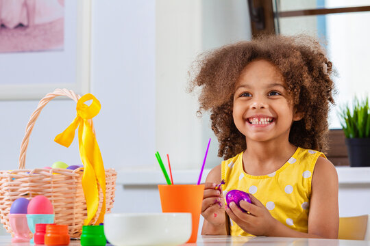Little with wide smile Black girl paint Easter eggs for Holiday