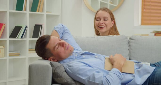 Young woman drawing on face of her husband while he is sleeping. April Fools Day prank