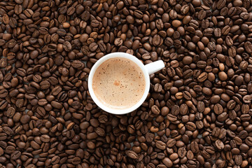White cup of espresso and roasted coffee beans as a background.