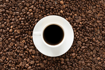 Coffee cup of fragrant coffee and coffee grains as a background. View from above