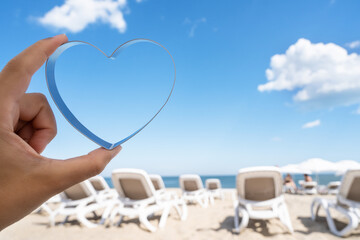 Fototapeta na wymiar Sea view through shape of heart in the female hand of tropical beach. Valentines day. Holiday, vacation concept. Creative, background, copy space, travel, summer.