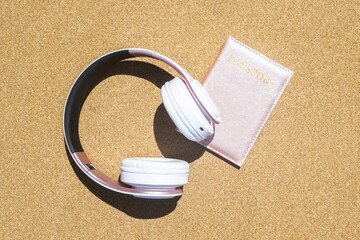 Passport in a cover, headphones lying on the sand of the beach. Concept of summer travel, tourism, holiday, vacation.