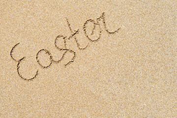 Drawing easter word on the sand on the beach.