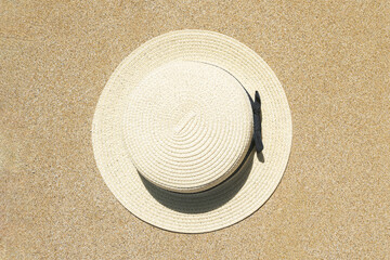 Fototapeta na wymiar Summer straw hat lying on sand of beach. Travel, holiday, summertime concept. Copy space. Top view. Flat lay
