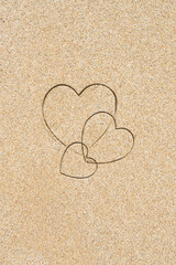 Fototapeta premium Hand-drawn shape of three heart on sand tropical beach. valentines day. Holiday, the vacation of family, friends concept. Creative, background, copy space, travel, summer. Flat lay