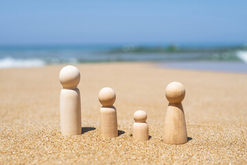  Wooden four figures of people on the sand of beach with sea view. Concept of happy family with two kids on holiday.