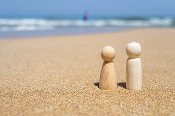 Wooden two figures of people on the sand of beach with sea view. Concept of happy couple on holiday.