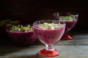 Homemade fruit dessert in a glass cup, on a wooden table.