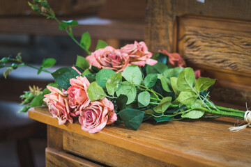 Bouquet of pink roses and green leaves over a wood table