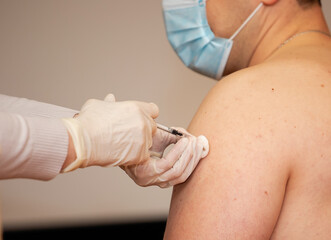 A person is injected with a syringe in the shoulder. Coronavirus vaccine. Vaccination and treatment of dangerous infections.