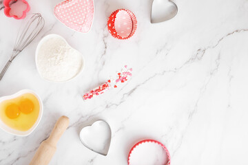 Ingredients and shapes for baking cakes on marble table. Concept cooking with love, cooking for your loved ones, baking for valentines day. Top view. Copy space