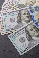 A bundle of close-up of one hundred dollar bills are spread out on a flat surface.