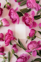 Blank paper card mockup with peonies flowers. Gentle boho floral composition with copy space on pink pastel background