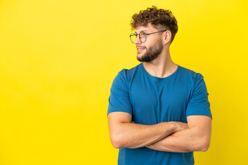 Young handsome caucasian man isolated on yellow background looking to the side