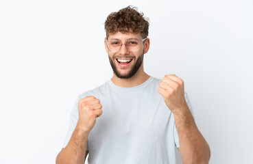 Young handsome caucasian man isolated on white background With glasses and celebrating a victory