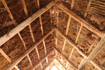 The reed roof on the house. Natural building materials.Texture of old thatched roof from the inside. Old technology. Wooden house architecture.