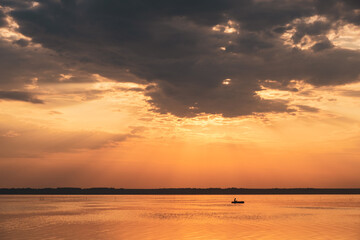Fototapeta premium lake landscape during sunset on a summer day. silhouette of a man in a boat on the lake