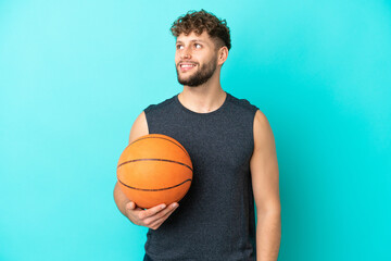 Obraz premium Handsome young man playing basketball isolated on blue background thinking an idea while looking up
