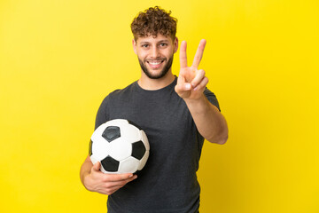 Handsome young football player man isolated on yellow background smiling and showing victory sign