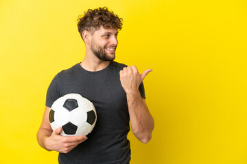 Handsome young football player man isolated on yellow background pointing to the side to present a product