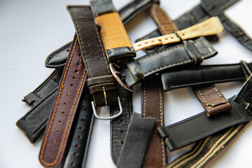 Old worn leather watch bracelets with a clasp in a pile.