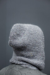 Close-up shot of a knitted woolen hood. Gray handmade alpaca sweater