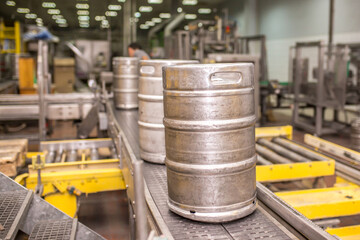 Brewery, bottling beer on aluminum kegs on conveyor lines. Industrial work, automated modern food and beverage production.