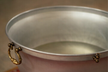 The edge of the baptismal bath. The handle and the tap are visible. Clear water is poured. Blurred background and foreground.