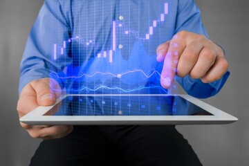 Businessman holding digital tablet 2022 stock market forecast outlook, charts and candlesticks