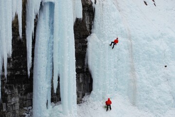 Two red clothed ice climbers on a frozen waterfall. 