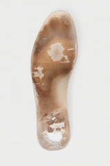 Old and shabby orthopedic insoles isolated on white background. Dirty leather insoles. Worn out things with holes. Inner soles of shoes. Top view banner close up.