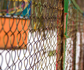 Close-up сracked oil paint on aged metal fence in winter park. Capped reticulated rusty lattice.