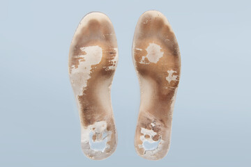 Two old, shabby orthopedic insoles isolated on blue background. Dirty leather insoles. Worn out things with holes. Inner soles of shoes. Top view banner close up.